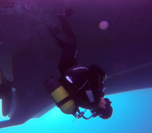 Yolda yürür gibi teknelerin altında baş aşağı yürüyor